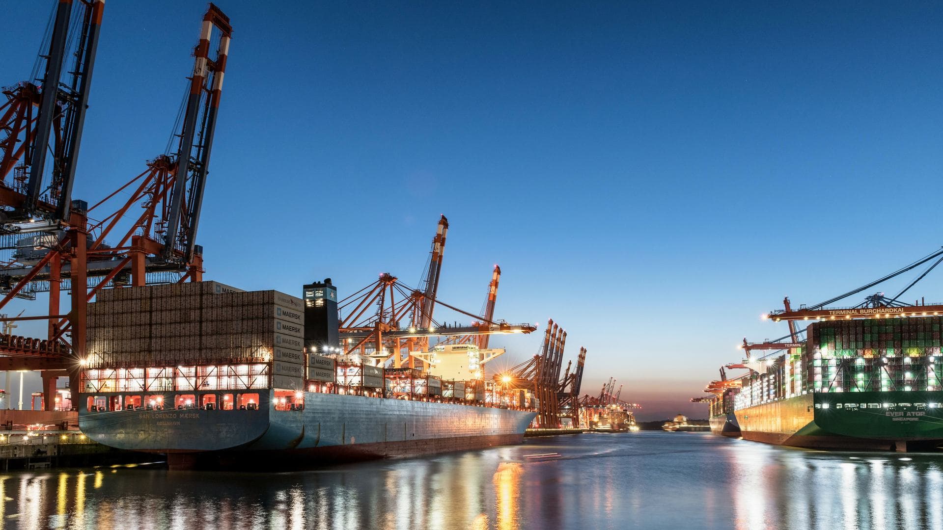 Container terminal at dusk with gantry cranes over berthed vessels